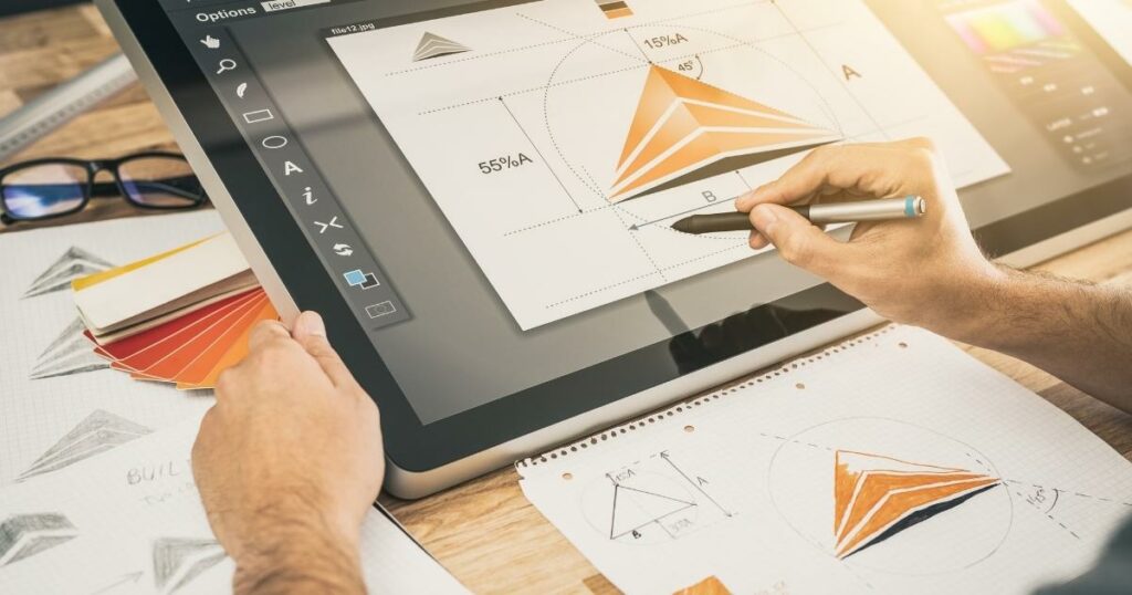 picture of a person sketching and creating a logo with a touch panel with glasses and sketch paper in fron t of him