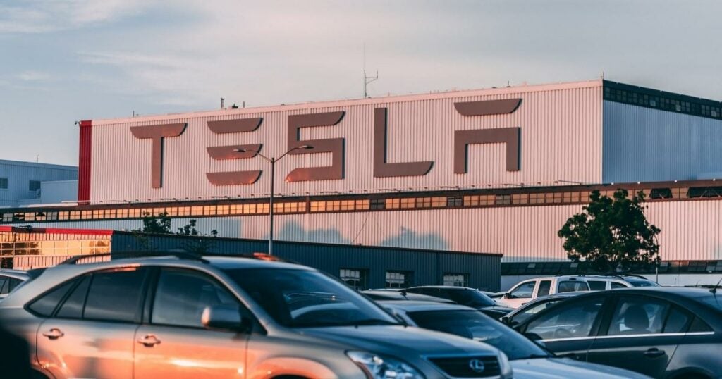 Tesla Headquarters with the big wordmark 'TESLA,' and cars parked.