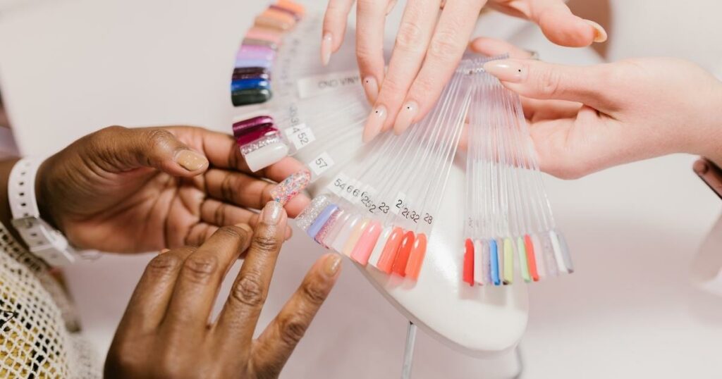 woman choosing nail polish colors among the color nail samples given to her by the nail technician. But the photo only shows the hands of the people
