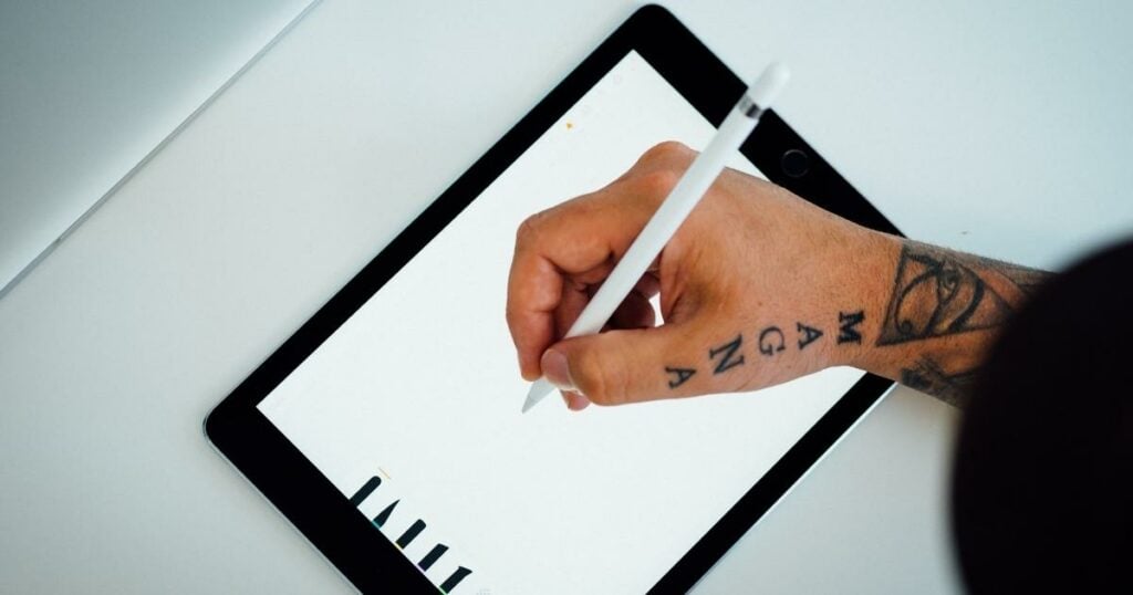A hand is sketching a logo on a tablet screen