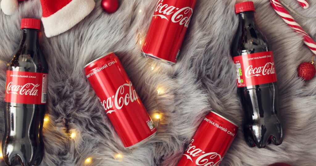photo of coca-cola in bottle and in can with placed on a furry mat with light bulb designs
