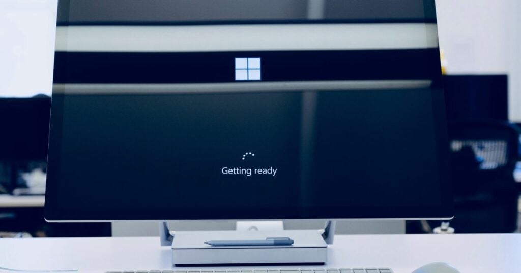 A loading Microsoft logo opening screen on a monitor on top of a white table.
