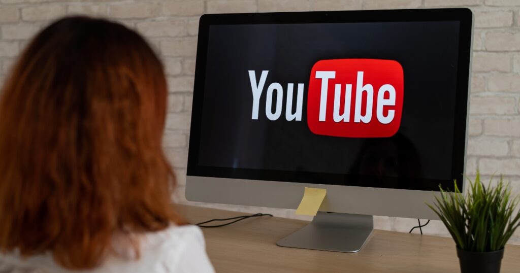 a woman using her monitor while the youtube logo was shown to her screen